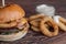 Closeup of a tasty Burger with appetizers such as fried onion rings with a white garlic sauce. Juicy Burger with bacon and cheese