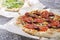 Closeup of tasty hot pizza with tomatoes, cheese, slices of grilled sausages, mushrooms and second one with arugular, different ki