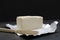 Closeup of tasty milky butter, knife on the packaging paper against dark background