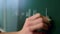 Closeup teacher arm writing on blackboard in class. Woman drawing on chalkboard