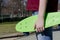 Closeup of teenage girl holding a green penny skateboard waiting to restart her skating activity