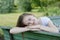 Closeup of teenage girl sitting, relaxing in the park, on a bench. Education, school girl. Smiling young woman. Summer time,