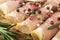 Closeup of thin slices of prosciutto with rosemary and paprika on wooden cutting board