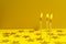 Closeup of three candles and flame, shiny stars glitter on the yellow background.Empty space