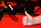 Closeup of a thumb up, symbol of a successful game against the red table and dark background, casino, copy space, place for text