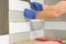 Closeup of tiler hand laying ceramic tile on wall in kitchen, renovation, repair, construction