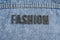 Closeup to a FASHION lettering black word over a gradient Blue jean texture