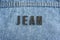 Closeup to a JEAN lettering black word over a gradient Blue jean texture