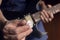 Closeup to a male hand holding a white guitar pick with a blurred black and yellow electric guitar at background