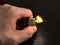 Closeup to a male hand holding a yellow lighter with flame over a dark wooden table