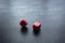 Closeup to a red dices, one dice is spinning over a black background.