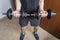 Closeup to a young man holding and squeezing an iron dumbbels with room background.