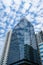 Closeup of top modern high-rise modern buildings. Mirroring of concrete skyscrapers on blue sky in shiny glass windows