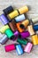 Closeup top view of colorful bobbins with sewing threads piled up on rustic wooden background with copy space