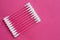 Closeup top view  on cotton buds laid in a diagonal line on pink background
