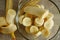 Closeup top view of pile of banana slices and a half of a banana fruit in a glass bowl and a peeling banana on side