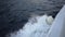 Closeup top view of wake behind large passenger ferry at sea on summer day. White foam trail behind ship created by the