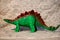 Closeup of a toy figurine of a green Stegosaurus dinosaur