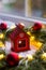 Closeup toy wooden winter house near fir wreath decorated with red Christmas balls and coiled with glowing garland with warm light