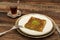 Closeup of traditional Turkish dessert - Kadayif with pistachio powder (Burma kadayif) on wooden background.