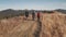 Closeup travelers walk at burnt grass mountain hill aerial. Wild fire at mount forest. People hike