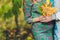 Closeup on tummy of pregnant woman, wearing long green dress, holding in hands bouquet of daisy flowers outdoors, new