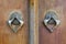 Closeup of two antique copper ornate door knockers over an aged wooden ornate door