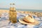 Closeup of two beer glass bottles on sandy tropical beach towel near straw hat. Blue ocean lagoon on background