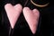 Closeup two big soft pink heart shaped handmade toys hanging on fishing line