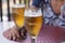 Closeup of two glasses of cold alcoholic beers, and woman`s hands