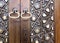 Closeup of two golden ring door knobs over an aged decorated wooden door