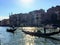 A closeup of two gondoliers taking tourists down the grand canal in their gondolas as the sun sparkles on the water