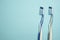 Closeup of two new plastic toothbrushes on a blue background.