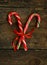 Closeup of two old fashioned candy canes on a rustic wooden back