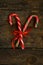 Closeup of two old fashioned candy canes on a rustic wooden back