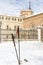 Closeup of two trekking poles nailed in the snow with the archiepiscopal palace of alcala de henares in the background