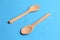Closeup of two wooden ladles pointing on the opposite direction on a blue surface