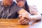 Closeup on two young lovers holding hands at a table, symbol sign sincere feelings, compassion, loved one, say sorry. Reliable