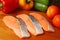 Closeup uncooked sliced salmons on a cutting board surrounded with colorful fresh vegetables