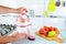 Closeup. Unrecognizable man presses carrot inside juicer to make tasty juice for breakfast from fresh vegetables, pours in