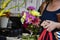 Closeup of unrecognizable woman with bouquet of beautiful flowers carrying cell phone and shopping bag and purse