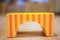 Closeup up of a yellow wooden arch block with orange stripes