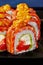 Closeup of uramaki roll with cream cheese, tobiko, avocado, seared salmon and mango