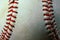 Closeup of a used white baseball with red seams.