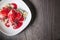 Closeup Vanilla ice cream poured with strawberry or raspberry jam with sliced banana slices on a white plate on a dark