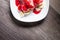 Closeup Vanilla ice cream poured with strawberry or raspberry jam with sliced banana slices on a white plate on a dark