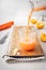 Closeup vertical shot of a fresh-squeezed orange juice glass poring from a transparent bottle