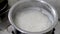 Closeup video of boiling of white rice in water in a steel sauce pan with steam