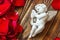 Closeup view of beautiful cupid with the trumpet, angel decorative figurine near red rose petals on wooden background.