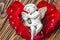 Closeup view of beautiful cupid with the trumpet, angel decorative figurine near red rose petals on wooden background.